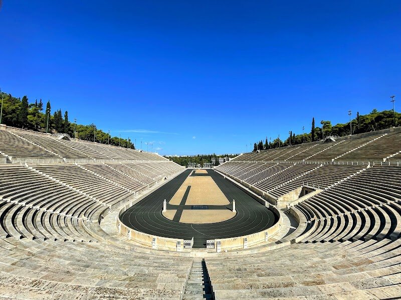 Panathenaic Stadium - The **Panathenaic Stadium** in Athens, known locally as Kallimarmaro (“beautifully marbled”), is a dazzling monument that bridges ancient tradition and modern celebration. Families and curious travelers alike will be captivated by its dramatic horseshoe shape, gleaming entirely in white marble—a sight unique in the world. Originally built in the 4th century BC to host the Panathenaic Games honoring Athena, the stadium was later transformed by the Romans and, centuries later, spectacularly revived for the first modern Olympic Games in 1896. Stepping inside, visitors can imagine the roar of 50,000 ancient spectators and the energy of athletes competing for glory. Today, you can walk or even jog around the historic track, reliving Olympic moments or simply soaking in the grandeur of this 2,300-year-old site. The stadium also hosts occasional concerts and the annual finish of the Athens Marathon, keeping its legacy alive for new generations. Whether you’re exploring as a family or seeking stories of sport and history, the Panathenaic Stadium offers a vivid journey through time, connecting the achievements of ancient Greece with the enduring spirit of the Olympics.