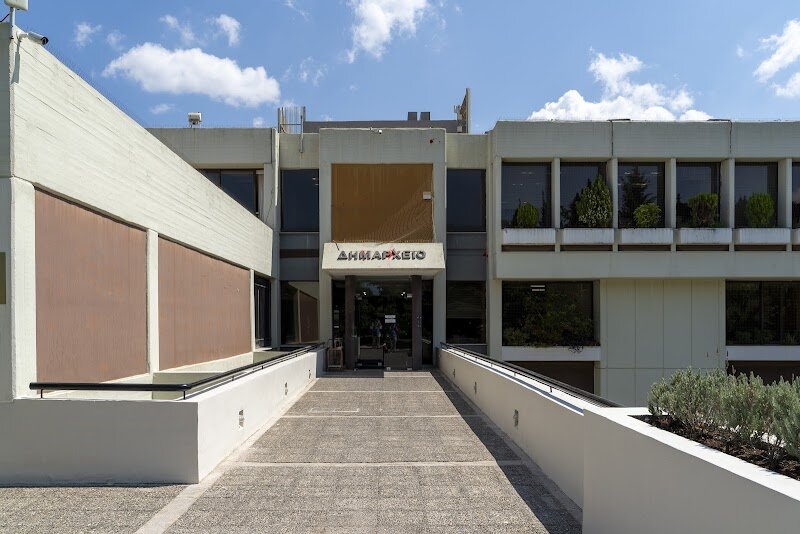 Cholargos Town Hall - ## Cholargos Town Hall: The Heart of a Modern Athenian Neighborhood Nestled in one of Athens’ most vibrant northern suburbs, Cholargos Town Hall stands as a proud symbol of community and local governance, seamlessly blending the city’s contemporary pulse with echoes of its storied past. While Athens is globally renowned for its ancient monuments and neoclassical grandeur, Cholargos offers a different kind of Athenian experience—one rooted in everyday life, civic pride, and the warmth of a close-knit neighborhood. The area itself has ancient roots, once a deme of classical Attica and famously home to Pericles, the golden age statesman. Today, Cholargos is a bustling, family-friendly district, and its Town Hall reflects this spirit of continuity and renewal. The building, though modern in design, embodies the democratic traditions that have shaped Athens for millennia, inviting visitors to witness local government in action and glimpse the daily rhythms of Athenian suburban life. Visitors can stroll through the lively surrounding streets, where cafés, parks, and local shops create a welcoming atmosphere for families and curious travelers alike. The Town Hall often hosts cultural events, exhibitions, and community gatherings, making it a lively hub where visitors can connect with locals and experience Athens beyond the tourist trail. Whether you’re interested in history, local culture, or simply soaking up the authentic vibe of a thriving Athenian community, Cholargos Town Hall offers a unique, engaging slice of modern Athenian life—where the past and present live side by side.