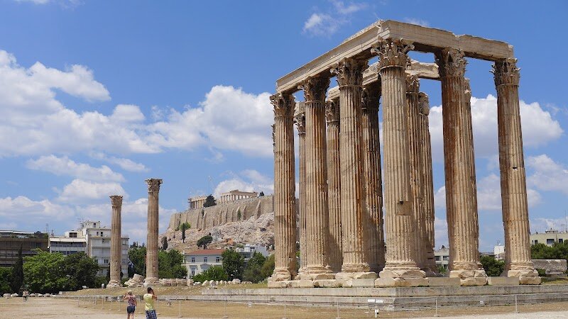 Temple of Olympian Zeus - The Temple of Olympian Zeus in Athens is a breathtaking testament to the city’s ancient grandeur and ambition, captivating families and curious travelers alike with its sheer scale and dramatic history. Rising near the heart of modern Athens, this colossal ruin was once the largest temple in Greece, boasting 104 towering columns—of which 16 still stand, offering an awe-inspiring glimpse into the past. Construction began in the 6th century BC, but the temple’s journey was anything but smooth; after centuries of delays and political upheaval, it was finally completed by the Roman Emperor Hadrian in 132 AD. Stepping onto the site, visitors are transported back to an era where gods and emperors mingled—Hadrian himself was honored with a grand statue alongside Zeus, the king of the Olympian gods. Children and adults can wander among the surviving columns, imagining the immense scale of the original sanctuary and the bustling ceremonies that once filled its marble expanse. The temple’s ruins, framed by the Acropolis in the distance, invite exploration and storytelling, making it a perfect destination for families seeking to uncover the myths, legends, and enduring mysteries of ancient Athens.