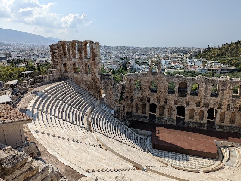 Theatre of Dionysus Eleuthereus - Step into the birthplace of drama at the **Theatre of Dionysus Eleuthereus** in Athens, where the magic of ancient Greek theatre first came to life. Nestled on the southern slope of the Acropolis, this remarkable site is considered the world’s oldest theatre and once hosted up to 17,000 spectators. Here, legendary playwrights like Sophocles, Euripides, and Aristophanes debuted their masterpieces, captivating Athenians during the vibrant City Dionysia festival—a spectacular celebration blending theater, religion, and community spirit. Families and curious travelers can wander among the stone tiers and imagine the thunderous applause that once greeted actors and choruses under the open sky. As you explore, you’re walking in the footsteps of citizens who gathered not just for entertainment, but to experience the heart of Athenian democracy and culture. Children will delight in stories of gods and heroes, while adults can reflect on how these ancient performances shaped Western art and thought. The ruins invite you to pause, listen for echoes of ancient voices, and connect with a tradition that has inspired audiences for over two millennia.