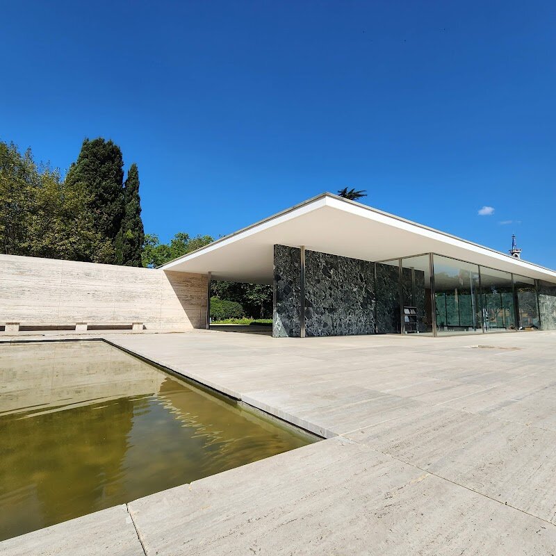Mies van der Rohe Pavilion - The Mies van der Rohe Pavilion in Barcelona is a stunning icon of modern architecture that invites families and curious travelers to step into a world of light, space, and elegant simplicity. Originally built for the 1929 International Exhibition, this pavilion was designed by Ludwig Mies van der Rohe and Lilly Reich to symbolize a new era for Germany—one of peace, progress, and innovation. Its minimalist design, crafted from glass, steel, and four types of beautiful marble, creates open, flowing spaces that feel both serene and inspiring. Visitors are welcomed into a tranquil environment where the play of natural light dances across reflective surfaces, and the famous “Alba” sculpture by Georg Kolbe mirrors itself in a shallow pool, offering a magical visual experience. You can admire the legendary Barcelona chairs—icons of modern design—while children and adults alike enjoy the freedom to explore the Pavilion’s unique layout and ever-changing perspectives. Beyond its beauty, the Pavilion’s story is compelling: dismantled after the exhibition, it was lovingly reconstructed in the 1980s and now hosts creative events and art installations, keeping its spirit alive for new generations. A visit here is not just about architecture—it’s about discovering how space, art, and history come together in one unforgettable place.