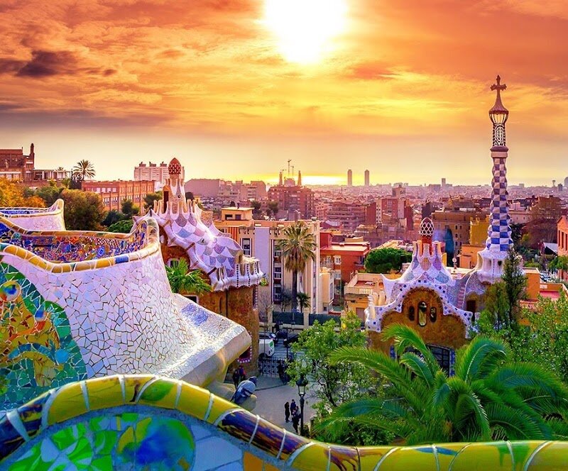 Park Güell - Park Güell is a fantastical playground of art and nature, perched atop Carmel Hill in Barcelona’s Gràcia district. Designed by the visionary architect Antoni Gaudí between 1900 and 1914, this vibrant park is a masterpiece of Catalan Modernism, where colorful mosaics, winding pathways, and whimsical sculptures turn every corner into an adventure. Originally conceived as a luxury residential estate by industrialist Eusebi Güell, the project evolved into a public space that now delights families and travelers from around the world. Step into Park Güell and you’ll be greeted by the iconic mosaic dragon at the entrance, followed by surreal pavilions and the famous serpentine bench, whose undulating curves invite visitors to relax and soak in panoramic views of Barcelona. Gaudí’s deep love for nature shines through in the organic shapes and Mediterranean gardens he created, blending architecture seamlessly with the landscape. Kids will marvel at the playful forms and bright colors, while curious explorers can uncover hidden symbols rooted in Catalan culture and mythology. Whether you’re picnicking on the sun-drenched terrace or exploring the enchanting colonnades, Park Güell promises a magical experience for all ages.