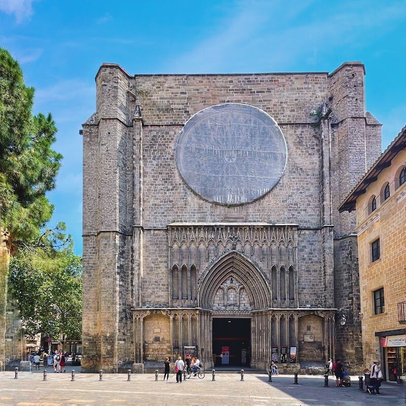 Basílica de Santa Maria del Pi - Tucked away in Barcelona’s enchanting Gothic Quarter, the **Basílica de Santa Maria del Pi** is a hidden gem that sparks the imagination of families and curious travelers alike. Rising above the labyrinthine streets, its imposing **bell tower**—one of the city’s tallest—beckons visitors to discover centuries of history and artistry. Built between the 14th and 15th centuries, this Catalan Gothic masterpiece stands on the site of earlier churches dating back as far as the 5th century, bearing witness to Barcelona’s rich and sometimes turbulent past, from medieval prosperity to the scars of the War of Succession and the Spanish Civil War. Step inside to marvel at the **soaring single nave**, one of the widest of its kind, where sunlight streams through the enormous **rose window**—among the largest in the world—casting vibrant patterns across the stone floor. Children will love exploring the quiet side chapels and spotting the pine tree that inspired the church’s name (“Pi” means pine in Catalan). With its blend of serene beauty, fascinating history, and the lively squares surrounding it, Santa Maria del Pi invites every visitor to experience the heart and soul of old Barcelona.