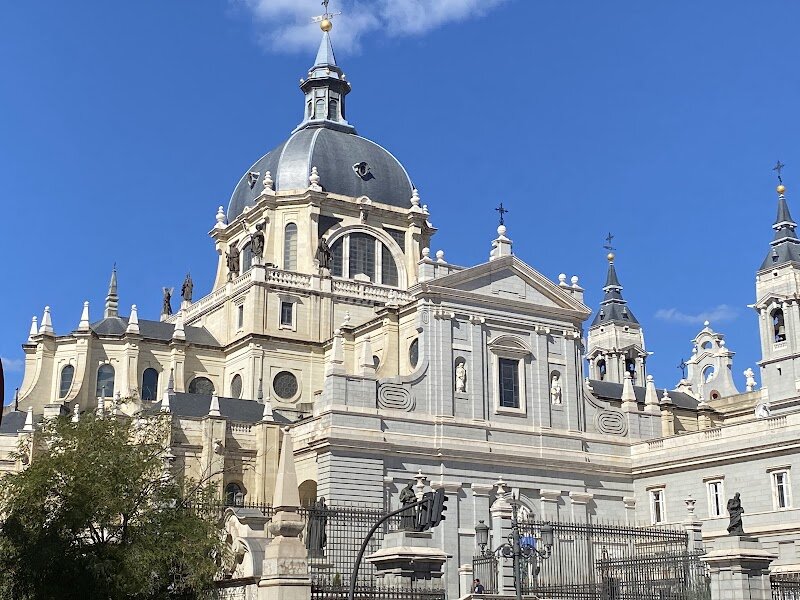 Catedral de Santa María la Real de la Almudena - The Catedral de Santa María la Real de la Almudena in Madrid is a captivating blend of history, devotion, and architectural beauty that appeals to families and curious travelers alike. Situated opposite the Royal Palace, this grand cathedral stands as a symbol of Madrid’s royal and spiritual heritage. Its construction began in 1883, originally intended as a pantheon for Queen María de las Mercedes, but evolved into the city’s main cathedral, consecrated by Pope John Paul II in 1993—the first cathedral consecrated outside Rome. What makes Almudena Cathedral truly special is its eclectic architectural style, combining Neo-Gothic, Neo-Romanesque, and Neo-Classical elements, harmonizing with the regal surroundings. Visitors are drawn to the revered statue of the Virgin of Almudena, Madrid’s patron saint, whose legendary discovery behind the city’s ancient walls inspires awe and devotion. Inside, families can explore beautiful stained glass, detailed murals, and numerous chapels, while history enthusiasts will appreciate the crypt housing Spanish monarchs’ remains. A visit here offers a rich experience—stepping into a place where royal history, religious tradition, and artistic splendor converge, inviting reflection and wonder for all ages.