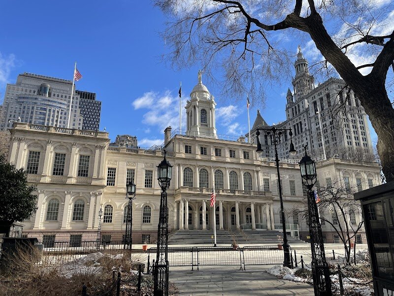 New York City Hall - New York City Hall, nestled in the heart of Lower Manhattan’s City Hall Park, is a living piece of American history and a must-see for families and curious travelers alike. As the **oldest city hall in the United States still serving its original governmental purpose**, this elegant landmark has been the stage for over two centuries of city life, from political milestones to public celebrations. Designed by Joseph-François Mangin and John McComb Jr. in the early 1800s, its architecture beautifully blends **Federal style with French influences**, featuring grand arched windows, delicate columns, and ornamental details that invite visitors to imagine the city’s storied past. Step inside—or stroll the surrounding park—and you’ll be following in the footsteps of New York’s leaders, activists, and everyday citizens. City Hall isn’t just a government building; it’s a vibrant symbol of democracy, resilience, and civic pride, having witnessed everything from 19th-century riots to 21st-century restorations. Families can marvel at the ornate interiors, discover fascinating stories of the city’s growth, and enjoy the greenery and monuments in City Hall Park—a perfect spot for both history buffs and young explorers to soak up the spirit of New York.
