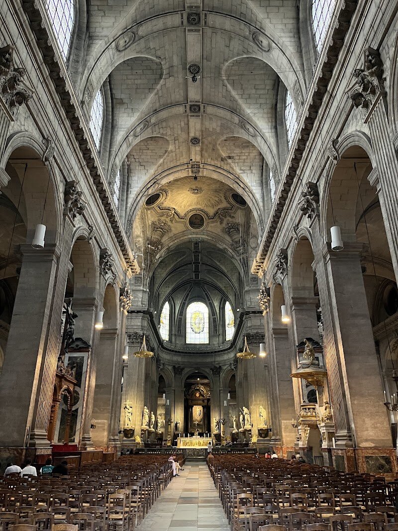 Église Saint-Sulpice - Église Saint-Sulpice, nestled in the lively heart of Paris’s 6th arrondissement, is a treasure for families and curious travelers eager to step into centuries of history and artistry. As the city’s second-largest church after Notre-Dame, its majestic facade—marked by grand colonnades and two famously mismatched towers—immediately captures the imagination, telling a story of evolving architectural styles and the ambitions of six architects over more than a century. Inside, sunlight streams through vast arched windows, illuminating a serene space where history whispers from every corner. Children and adults alike will be fascinated by the church’s monumental organ, one of the world’s largest, which still fills the nave with music during concerts and services. Art lovers can marvel at dramatic murals by Eugène Delacroix in the Chapelle des Anges, while keen-eyed visitors might spot the faint inscription above the entrance—a relic from the French Revolution when the church was transformed into a “Temple of Victory”. Whether you’re tracing the steps of literary legends or simply enjoying the peaceful ambiance, Saint-Sulpice offers a captivating blend of Parisian heritage, artistic wonder, and family-friendly discovery.