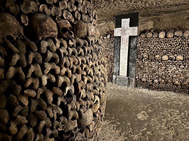 Catacombs of Paris - Venture beneath the bustling streets of Paris and you’ll find one of the city’s most intriguing and mysterious sites: the **Catacombs of Paris**. This vast underground labyrinth holds the carefully arranged bones of more than six million Parisians, transferred here in the late 18th and 19th centuries when overflowing cemeteries became a serious health concern. Walking these dimly lit tunnels, families and curious travelers can marvel at the artistry of the bone displays and imagine the stories of people from all walks of Parisian life—from plague victims to figures of the French Revolution. Beyond the eerie beauty, the Catacombs offer a fascinating window into Paris’s history. The site was once a network of limestone quarries, which provided the stone for many of the city’s famous monuments. Today, visitors can wander through galleries lined with skulls and femurs, discover ancient fossils embedded in the walls, and learn about the city’s creative solutions to urban challenges centuries ago. The Catacombs invite guests of all ages to step into a hidden world where history, geology, and legend intertwine—making it an unforgettable adventure for the whole family.