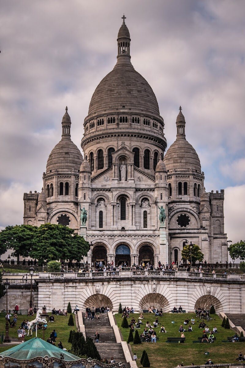 Basilique du Sacré-Cœur de Montmartre - The Basilique du Sacré-Cœur de Montmartre is one of Paris’s most enchanting landmarks, inviting families and curious travelers to discover its breathtaking beauty and rich history. Perched atop Montmartre hill—the city’s highest point—the basilica’s gleaming white domes are visible from across Paris, offering visitors panoramic views that captivate both young and old. Built after the turmoil of the Franco-Prussian War and the Paris Commune, Sacré-Cœur was envisioned as a symbol of hope, unity, and national renewal. Its striking Romano-Byzantine architecture sets it apart from other Parisian churches, while the interior boasts one of France’s largest mosaics, depicting Christ in Majesty, and a tradition of perpetual adoration that gives the space a sense of peace and wonder. Families can explore the legendary story of Saint Denis, the patron saint of Paris, said to have been martyred on this very hill. The surrounding Montmartre neighborhood, once a village of windmills and artists like Van Gogh and Picasso, adds a lively, creative spirit to your visit. Whether you’re marveling at the basilica’s soaring ceilings, listening to music in its echoing dome, or simply soaking in the sweeping cityscape, Sacré-Cœur promises an inspiring experience for all ages.