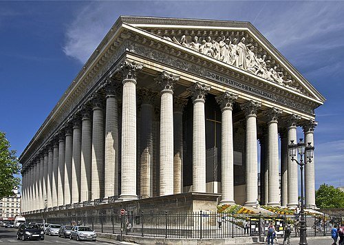 La Madeleine - La Madeleine, with its majestic neoclassical columns rising above the bustling Place de la Madeleine, is one of Paris’s most striking and storied landmarks—a place where history, architecture, and culture converge in the heart of the city. Unlike the city’s famous Gothic cathedrals, La Madeleine stands apart with its bold design inspired by ancient Roman temples, completely encircled by 52 towering Corinthian columns that evoke a sense of timeless grandeur. Originally commissioned by Napoleon as a “Temple of Glory” to honor his army, the building’s purpose shifted dramatically with changing regimes, finally being consecrated as a church in 1842. This dramatic history is etched into every stone, making a visit here a journey through France’s turbulent past—from monarchy to empire and beyond. Families and curious travelers will find much to explore: from the intricate bas-reliefs on the façade depicting biblical scenes to the serene, luminous interior where world-class classical concerts echo beneath soaring ceilings. La Madeleine is also famous as the site of Chopin’s poignant funeral, and its celebrated organ continues to draw music lovers today. Surrounded by Paris’s elegant boulevards and gourmet shops, La Madeleine offers an inspiring blend of art, history, and living tradition—inviting every visitor to experience a unique chapter of Parisian life.
