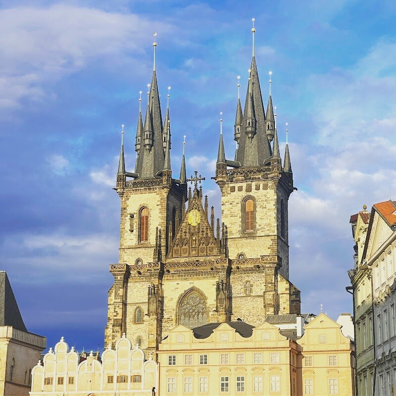 Church of Our Lady before Týn - The **Church of Our Lady before Týn** rises dramatically over Prague’s Old Town Square, its twin Gothic spires instantly capturing the imagination of visitors young and old. With towers soaring 80 meters high—one larger than the other, symbolizing Adam and Eve—this church is not only an architectural marvel but also a treasure trove of stories and legends. Some even say the towers inspired Disney’s Sleeping Beauty Castle, adding a touch of fairy-tale magic to the skyline. Built on the site of an earlier Romanesque church, the current structure took shape in the 14th and 15th centuries, guided by the same master builders behind St. Vitus Cathedral. Over the centuries, it witnessed turbulent religious change: it was a Hussite stronghold, then recatholicized, its golden chalice replaced by a radiant statue of the Virgin Mary. Inside, families and curious travelers can marvel at a Baroque interior, evocative altar paintings, and the city’s oldest organ, dating from 1673. The tomb of famed astronomer Tycho Brahe and intricate Gothic details add to its allure. Whether basking in daylight or shimmering at night, the Church of Our Lady before Týn offers a journey through Prague’s layered history, art, and legend—an experience not to be missed.