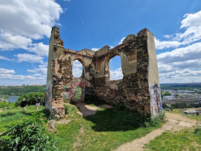 Baba ruins - Perched high above the Vltava River, the **Baba ruins** in Prague offer families and curious travelers a magical blend of history, mystery, and panoramic city views. These evocative stone remains crown Baba Hill in the Dejvice district, where legends and facts intertwine: some say the structure was once a vineyard press from the 17th century, others claim it was a summer house, or even a chapel. What sets Baba apart is its transformation in 1858, when railway builders reshaped the ruins into a romantic, castle-like folly—perfect for sparking the imagination of visitors of all ages. The hill itself has been a gathering place since the Stone Age, and archaeological finds reveal that people have admired this vantage point for millennia. Today, you can wander among the weathered stones, let children explore the nooks and crannies, and soak in sweeping views of Prague’s rooftops and the meandering river below. The site is freely accessible and illuminated at night, making it an inspiring spot for sunset picnics, family adventures, and anyone eager to experience a different, enchanting side of Prague’s history.