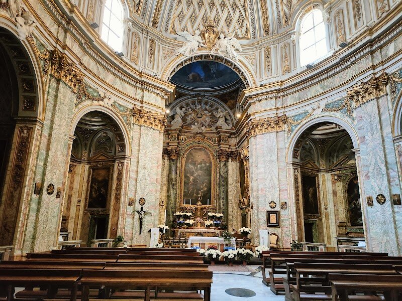 Santissima Trinità degli Spagnoli - Santissima Trinità degli Spagnoli is a hidden jewel in Rome, perfect for families and curious travelers eager to discover a place where history, art, and culture intertwine. Nestled at the start of the glamorous Via Condotti, just steps from Piazza di Spagna, this late Baroque church offers a striking contrast to the surrounding world of fashion boutiques and bustling city life. Built between 1741 and 1746 by the Spanish Trinitarian order, the church was designed by Portuguese architect Emanuele Rodriguez dos Santos and stands as one of Rome’s national churches of Spain. What makes this church truly special is its fascinating heritage: the Trinitarians were founded in the 12th century to ransom Christian captives, a mission reflected in the art and symbolism adorning the façade and interior. Families will appreciate the dramatic stucco group above the entrance, depicting an angel freeing enslaved captives—a powerful story for young minds to ponder. Step inside to experience an elegant elliptical nave, crowned by vibrant frescoes and original 18th-century paintings, including Corrado Giaquinto’s moving altarpiece of the Trinity liberating a slave. The rich faux marble, intricate stuccoes, and serene chapels invite exploration and quiet reflection, making Santissima Trinità degli Spagnoli a memorable stop on any Roman adventure.