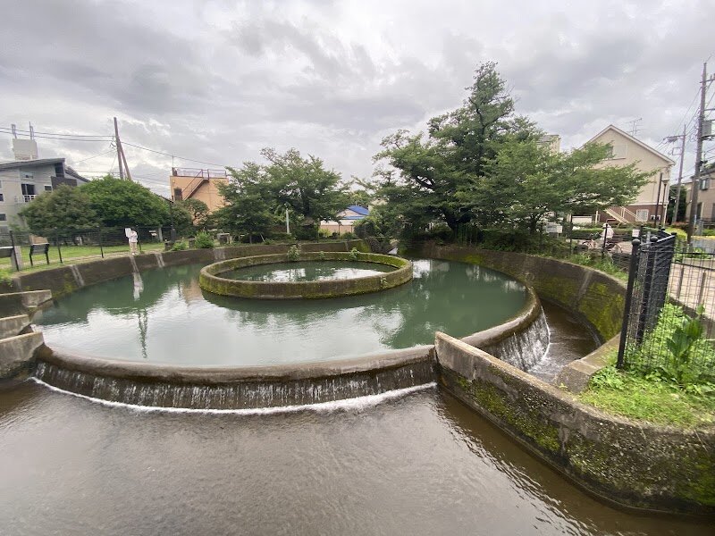 Kuji Cylindrical Water Divider - Discover the **Kuji Cylindrical Water Divider**, an ingenious blend of engineering and tranquility tucked away in Kawasaki’s Takatsu Ward, just south of Tokyo. Completed in 1941, this unique circular structure was designed by Hiraga Eiji to solve a centuries-old challenge—fairly dividing water from the Nigaryō Canal among local farmers, ending generations of disputes during droughts. Today, it stands not only as a marvel of Japanese water management but also as a registered National Tangible Cultural Property, celebrated for its elegant simplicity and lasting impact. Families and curious explorers will delight in seeing how the main cylinder—measuring a striking 16 meters across—divides water precisely into four channels, each serving different neighborhoods. The surrounding area, once fertile farmland, now flourishes with cherry blossoms in spring and attracts wild birds like spot-billed ducks and starlings, creating a peaceful haven for both people and wildlife. Visitors can stroll along the adjacent Nikaryō Canal, watch the gentle overflow of water, and reflect on a piece of history that quietly shaped the community. The Kuji Cylindrical Water Divider invites you to explore Tokyo’s hidden stories, where innovation meets the beauty of everyday life.