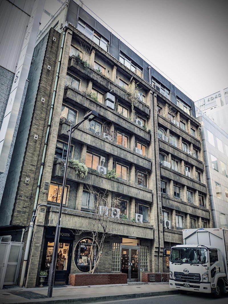 Okuno Building - Step into the Okuno Building and discover a rare slice of Tokyo’s past nestled in the heart of Ginza. Built in 1932 as a symbol of luxury and resilience, this early Shōwa-era landmark has survived war, earthquakes, and the city’s relentless modernization—making it one of Tokyo’s oldest apartment buildings still standing. Today, the Okuno Building charms families and curious travelers alike with its evocative hallways, original manually operated elevator—said to be Japan’s first in a private residence—and a fascinating blend of art galleries and antique shops spread across its seven floors. Wander through corridors worn by generations, admire the quirky architectural features like the round window and the odd passageways connecting the original and annexed buildings, and peek into spaces like Room 306, a living timeline now home to creative projects. Each gallery and boutique offers a new story, while preserved details—from scratch tiles to wooden banisters—invite you to imagine the glamorous lives of the artists, musicians, and celebrities who once called these apartments home. For families and explorers, the Okuno Building is more than a historic site—it’s a vibrant, ever-evolving museum where Tokyo’s history and creativity come alive around every corner.