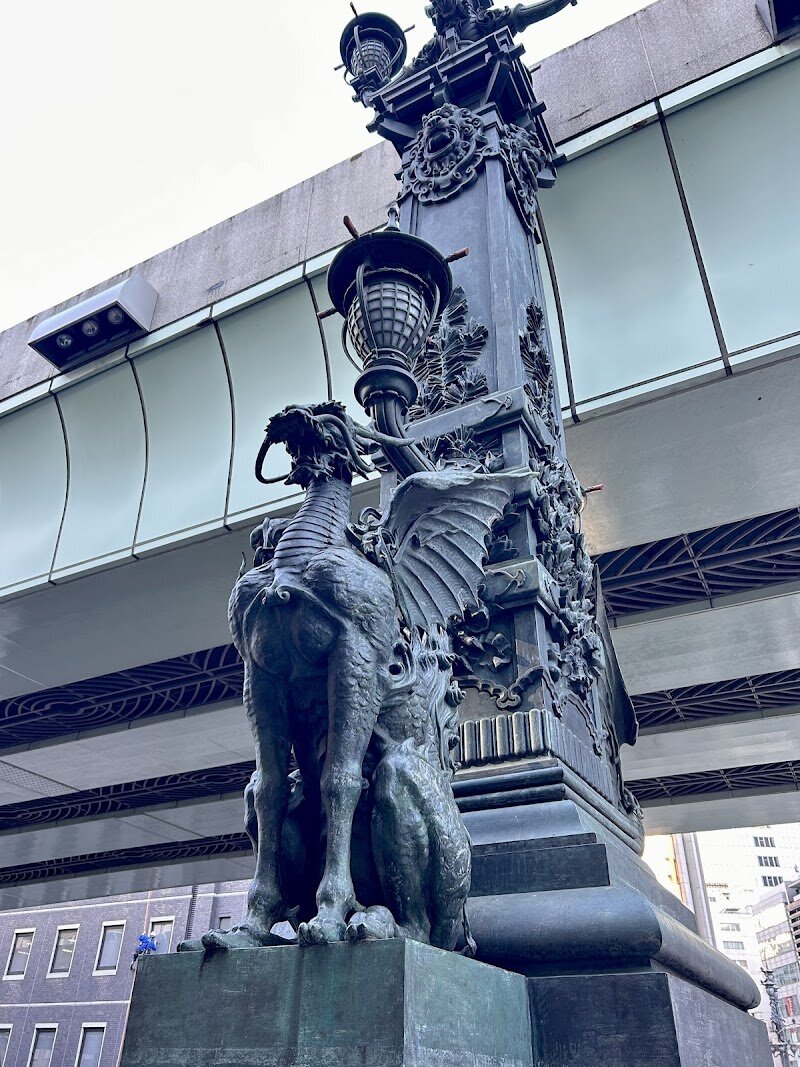 Statues of Kirin - The **Statues of Kirin** on Tokyo’s historic Nihonbashi Bridge are a captivating blend of art, mythology, and urban legend, making them an unforgettable stop for families and curious travelers alike. Rising over the heart of Chuo City since 1911, these bronze sculptures depict the mythical **Kirin**—a revered creature in Japanese folklore symbolizing prosperity and good fortune. What sets these statues apart is their unique design: unlike traditional kirin, these feature majestic wings, a creative flourish meant to reflect Tokyo’s soaring ambitions and innovative spirit. Beyond their artistic beauty, the statues mark Japan’s traditional “kilometer zero,” the symbolic center of the nation, linking centuries of history to the vibrant cityscape that surrounds them. Visit at dusk or night to experience the statues aglow with lantern light, when their intricate details and mythical aura truly come alive—an enchanting sight that delights children and adults alike. The area is perfect for leisurely strolls, photography, and exploring nearby shops and eateries, offering a rich tapestry of tradition and modernity. A visit to the Statues of Kirin is more than a photo opportunity; it’s a journey through Japan’s cultural heart, where legends and city life meet.