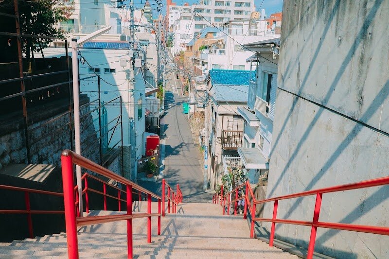 Your Name Stairs - The **Your Name Stairs** at Suga Shrine in Yotsuya, Tokyo, are a magical destination for families and curious travelers drawn to both anime and authentic Japanese culture. These picturesque steps, distinguished by their striking red railings, became world-famous as the setting for the emotional climax of Makoto Shinkai's animated masterpiece, *Your Name.* This film, which captivated millions globally, tells the story of two teenagers whose lives intertwine across time and space—culminating in a memorable reunion on these very stairs. What makes this spot truly special is its blend of everyday Tokyo life and cinematic history. Locals pass by as part of their routine, but for fans and newcomers alike, the stairs transform into a symbolic gateway where fiction meets reality. Visitors can relive scenes from the movie, snap photos at the exact location featured in film posters, and experience the unique thrill of standing where beloved characters once did. The area’s tranquil charm, combined with its proximity to central Tokyo attractions, makes it a perfect stop for families seeking both adventure and a touch of movie magic. Whether you’re a longtime anime fan or simply curious, the Your Name Stairs promise a memorable, heartwarming experience in the heart of Tokyo.