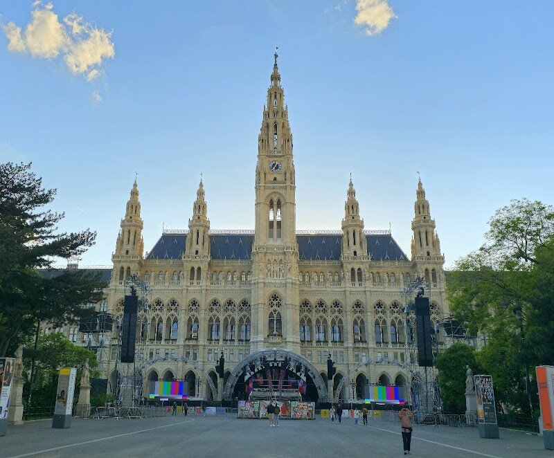 Vienna City Hall - Vienna City Hall, or Wiener Rathaus, stands as one of Europe's most magnificent civic buildings and a true symbol of Vienna's transformation in the 19th century. This stunning neo-Gothic masterpiece was designed by Friedrich von Schmidt and completed in 1883, rising majestically along the famous Ringstrasse boulevard. The building's soaring 98-meter tower, crowned with the iconic Rathausmann statue, dominates Vienna's skyline with its elegant pointed arches and richly decorated facade. What makes it truly special is the clever architectural ingenuity—the tower was deliberately kept just below the height of the nearby Votivkirche to respect the Emperor's wishes, yet the architect added a five-meter statue on top to achieve the desired grandeur. Inside, visitors discover Austria's largest historical ballroom and one of Europe's most impressive arcaded courtyards, originally designed as welcoming spaces for public gatherings. The building's intricate stonework features statues of Austrian rulers and figures representing justice and traditional trades, reflecting the rise of Vienna's bourgeoisie during this transformative era. Whether admiring its Gothic Revival architecture or exploring its grand interior spaces, Vienna City Hall offers a fascinating glimpse into 19th-century ambition and civic pride.